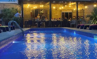a swimming pool at night with people sitting at a restaurant at Masia Notari Casabona in Vilanova i la Geltrú