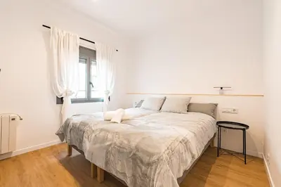 a white bedroom with a large bed with a window at Apartamento reformado de 3 habitaciones en Sagrada Familia in Barcelona