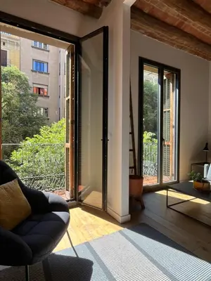 a living room with a chair and a large window at Spacious and cozy apartment in Barcelona