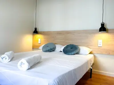 a large white bed with blue pillows on it at Apartment Goya in Vilanova i la Geltrú