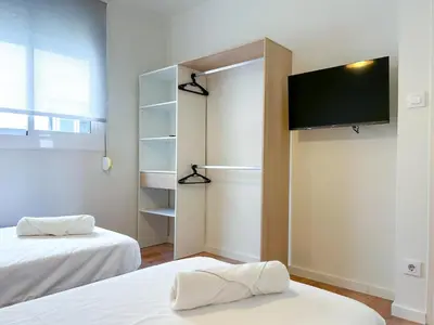 a room with two beds and a flat screen tv at Apartment Goya in Vilanova i la Geltrú