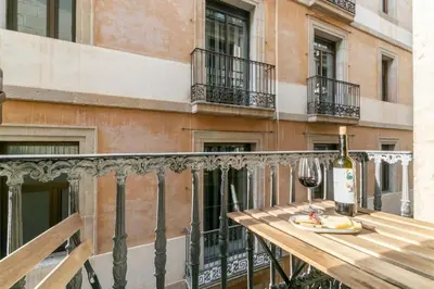 a wooden table with a bottle of wine on a balcony at BOLIVIA. NEWLY RENOVATED FULL APARTMENT WITH BRIGHT TERRACE in Barcelona