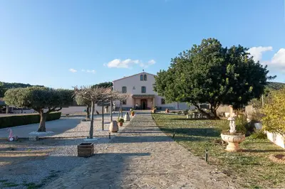a pathway leading to a large white building with trees at Masía con encanto para parar y desconectar in Castellví de la Marca