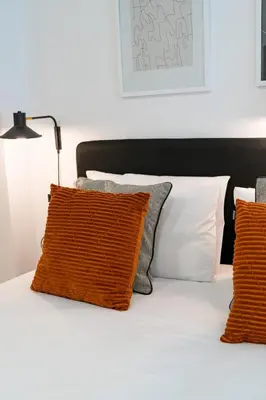 a bed with orange and white pillows and a lamp at Stay U-nique Apartments Barcelona Albeniz in El Arrabal