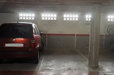 a red car parked in a parking garage at Apartamento Mallorca, muy cerca de la playa in Sitges