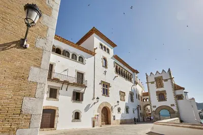 a large white building with a clock tower next to it at Apartamento Mallorca, muy cerca de la playa in Sitges