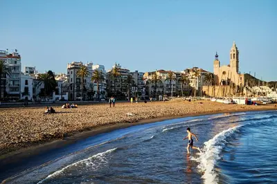 a person walking in the water on a beach at Santa Barbara, in downtown Sitges in Sitges