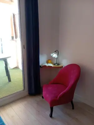 a red chair sitting in a room next to a window at Apartamento 2º centrico con Parking en Calella,Barcelona in Calella