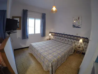 a bedroom with a bed and a tv and a window at Apartamentos Montserrat in Sitges