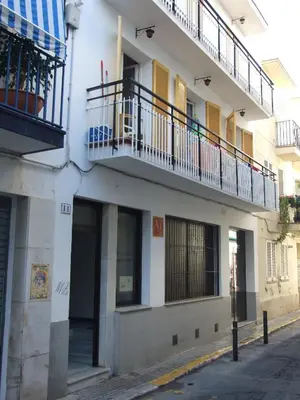 a white building with a balcony on a street at Apartamentos Montserrat in Sitges
