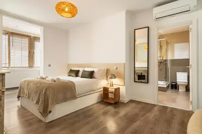 a white bedroom with a bed and a bathroom at Eixample Pedestrian Gem Balcony Bathtub AC in Barcelona