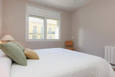 a white bedroom with a bed and two windows at ApartEasy mid-term ONLY for VACATIONS stays, EIXAMPLE CENTER in Barcelona