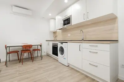 a kitchen with white cabinets and a table and chairs at Apartahotel Sant Marti Suites in San Martín Sarroca