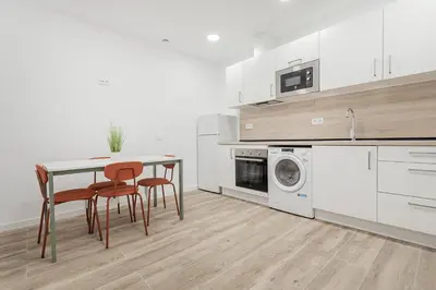 a kitchen with a table and chairs and a washing machine at Apartahotel Sant Marti Suites in San Martín Sarroca