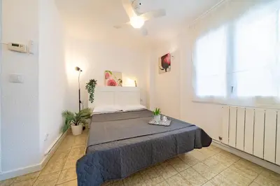 a white bedroom with a bed and a window at HomeHolidaysRentals Olimpia - Costa Barcelona in Pineda de Mar