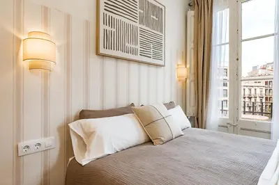 a bedroom with a bed with two lamps and a window at Lovely Apartment with Balcony in Sagrada Familia in Barcelona