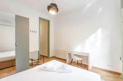 a white room with a bed and a desk at Modernist Apartment 2 in Barcelona