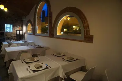 a dining room with white tables and chairs and windows at Hotel Can Ribalta in San Antonio de Vilamajor