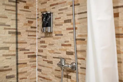 a shower with a black soap dispenser on a wall at Laramond Barcelona Rooms in Barcelona