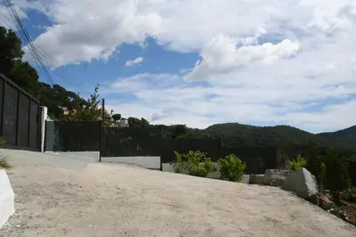 a dirt road with a fence and mountains in the background at Casa ceca de la Playa y Barcelona, con piscina climatizada y jacuzzi in Vallromanas