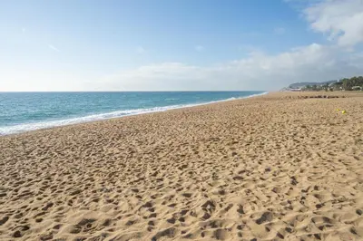 a sandy beach with the ocean in the background at HomeHolidaysRentals Pinedalovers - Costa Barcelona in Pineda de Mar