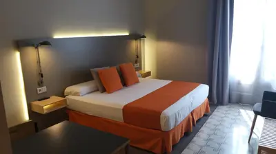 a hotel room with a large bed with orange pillows at Casa Abamita in Barcelona