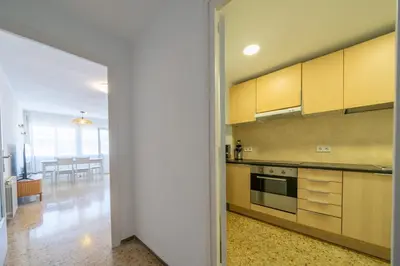 a kitchen with yellow cabinets and a dining room at HomeHolidaysRentals Magic - Costa Barcelona in Pineda de Mar