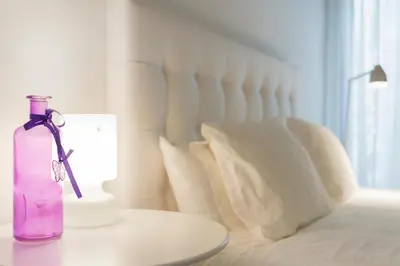 a purple bottle sitting on a table next to a bed at Casa De Poble Termes Romanes in Caldes de Montbui