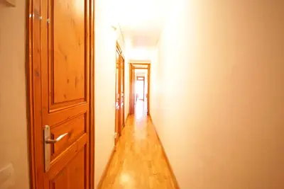 an empty hallway with an open door and a wooden floor at Flateli Aribau in Barcelona