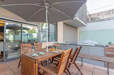 a wooden table with chairs and an umbrella on a patio at My Space Barcelona Gracia Pool Terrace in Barcelona