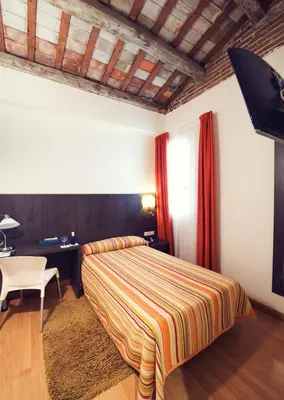 a bedroom with a bed and a table and a desk at Hotel Miramar Badalona in Badalona