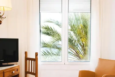 a room with a window with a television and a palm tree at Hotel Miramar Badalona in Badalona