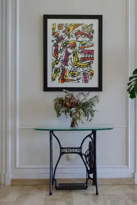 a table with a vase on it next to a painting at Hotel Miramar Badalona in Badalona