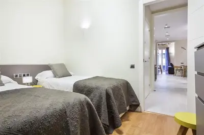 two beds in a white room with a hallway at Alcam Trafalgar in Barcelona