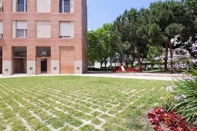 a brick building with a grass field in front of a building at Stay U-nique Apartments Salvador Espriu in Barcelona