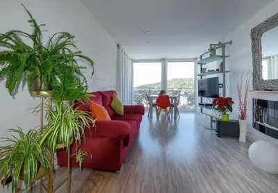 a living room with a red couch and some plants at Apartamento Reisol in Castelldefels