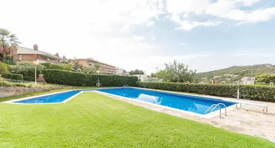 a swimming pool in a yard with green grass at Apartamento Reisol in Castelldefels