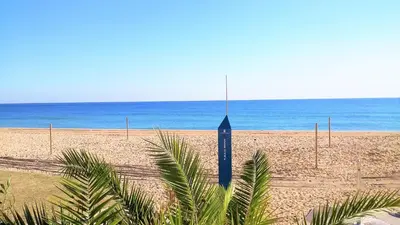 a clock on a beach with the ocean in the background at Bianca Seaview & Beach Apartment in Montgat