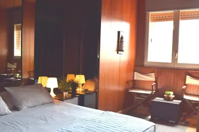 a bedroom with a bed and a chair and windows at Duplex Berlin 87 in Barcelona