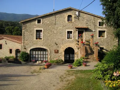 a large stone building with a door and a courtyard at Can Marc in Sant Esteve de Palautordera