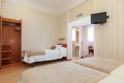 a hotel room with two beds and a flat screen tv at Hostal Oliva in Barcelona
