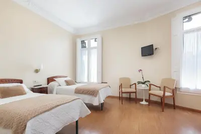a bedroom with two beds and a tv on the wall at Hostal Oliva in Barcelona