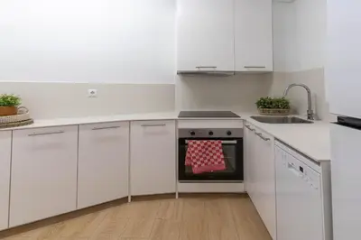 a kitchen with white cabinets and a red oven mit at Gran apartamento Sagrada Familia in Barcelona