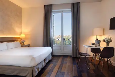 a hotel room with a bed and a desk and a window at Duquesa Suites Landmark Hotel by Grup Duquessa in Barcelona