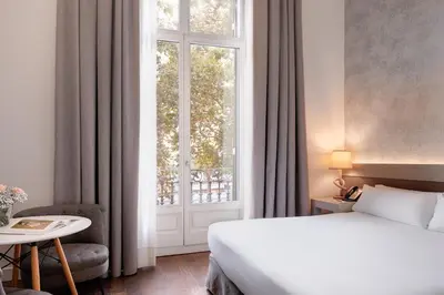 a bedroom with a bed and a large window at Duquesa Suites Landmark Hotel by Grup Duquessa in Barcelona