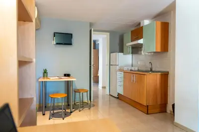 a kitchen with a table and two stools in it at Apartaments Turístics Residencia Vila Nova in Vilanova i la Geltrú