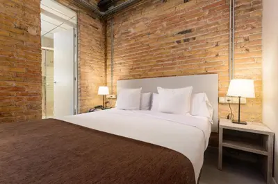 a bedroom with a large bed and a brick wall at Apartamentos DV in Barcelona