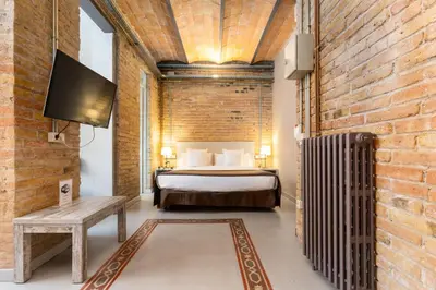a bedroom with a bed and a brick wall at Apartamentos DV in Barcelona
