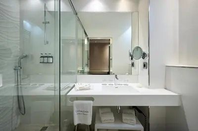 a white bathroom with a sink and a shower at Catalonia Magdalenes in Barcelona