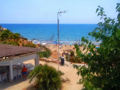 a beach with a windmill and people on the beach at Apartment Aloha Sitges in Sitges